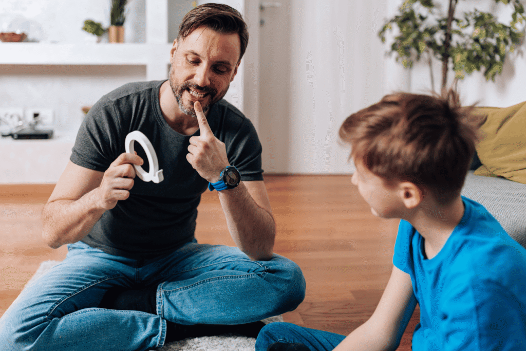 Male speech therapist sitting down on the ground helping a child with sensory processing differences