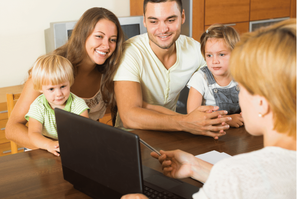 DCC Foster Care Practitioner guiding a family of four by pointing at computer screen